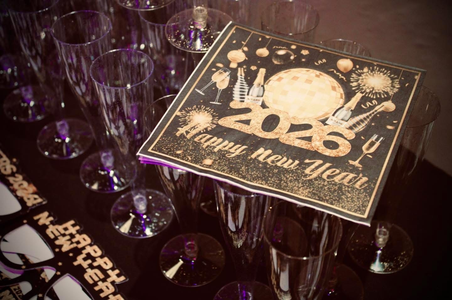 Happy New Year 2026 napkins beside champagne glasses