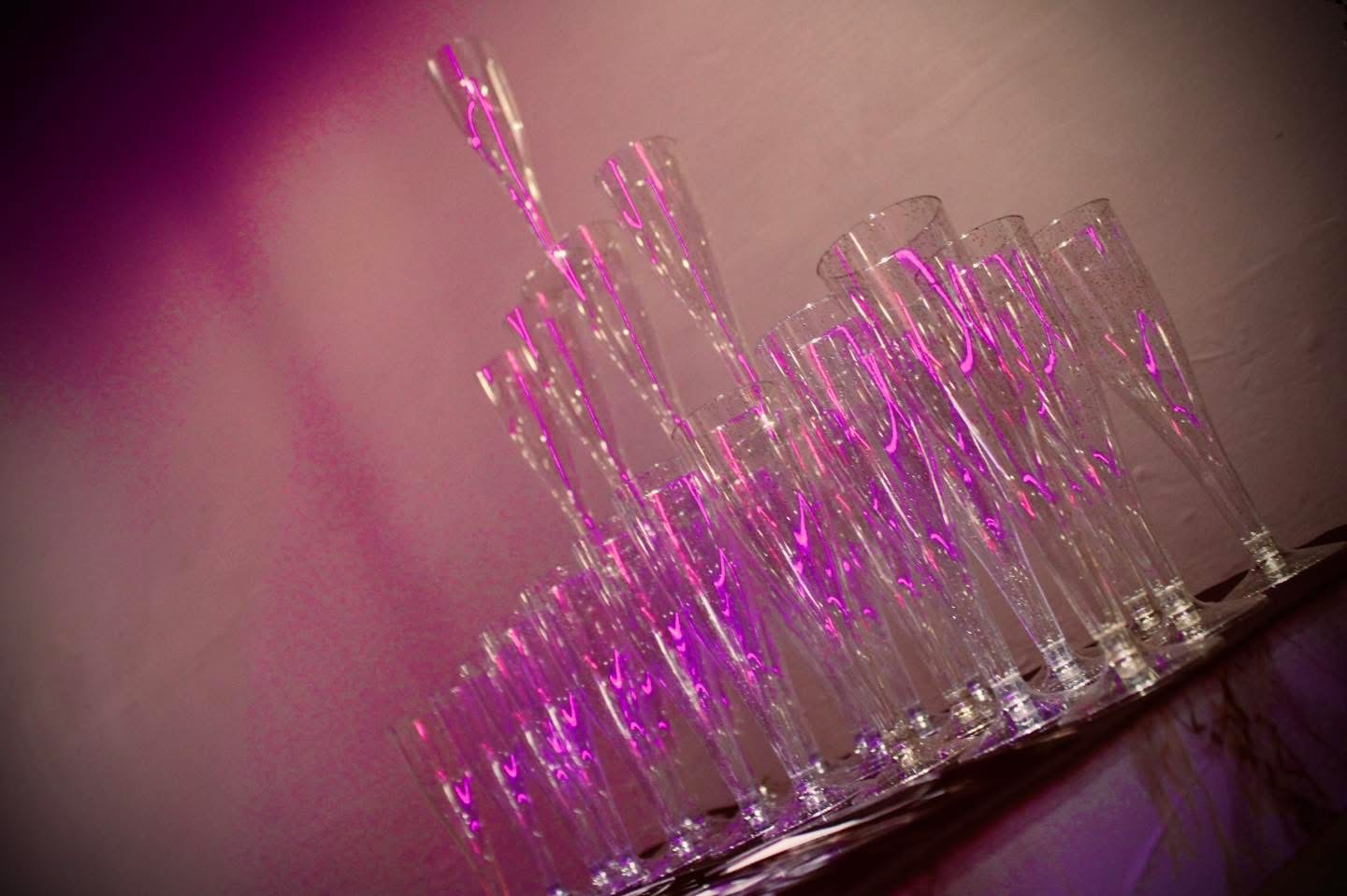 Champagne flutes lit by pink party lighting