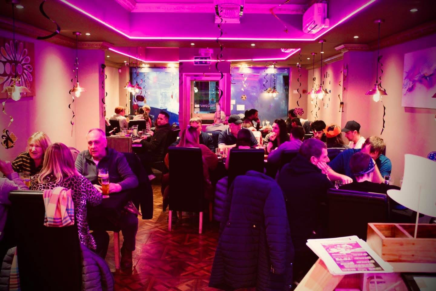Guests dining together in the neon-lit dining room at Fusion Spice, Moortown