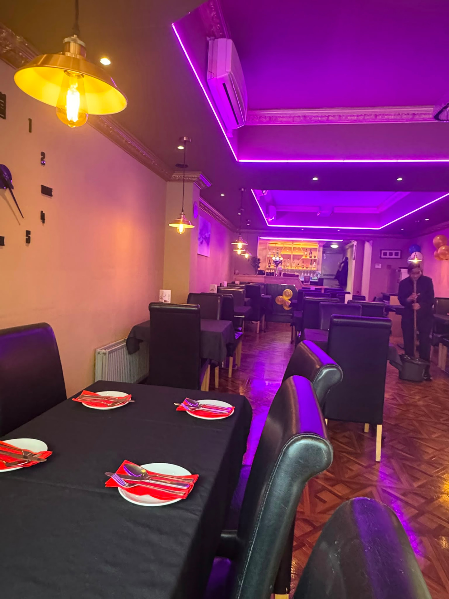 Long tables laid up with red napkins under neon lighting